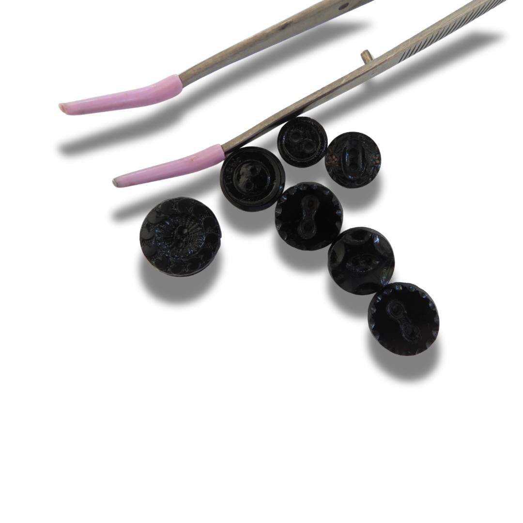 Set of 7 antique Victorian black glass buttons for sewing - 2-hole, 8–15 mm, Czech molded glass. Glossy floral & geometric patterns