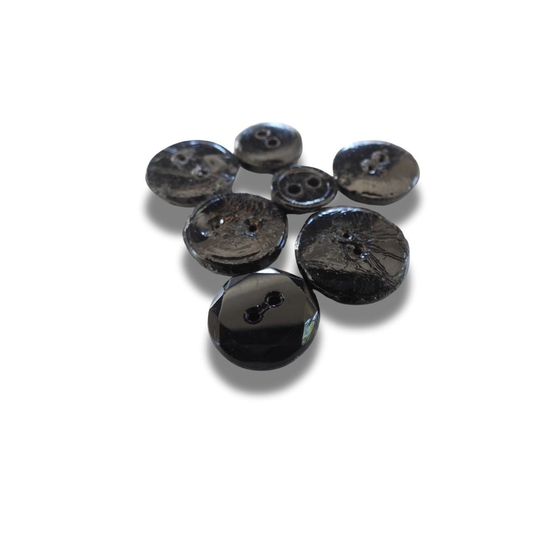 Set of 7 antique Victorian black glass buttons for sewing - 2-hole, 8–15 mm, Czech molded glass. Glossy floral & geometric patterns