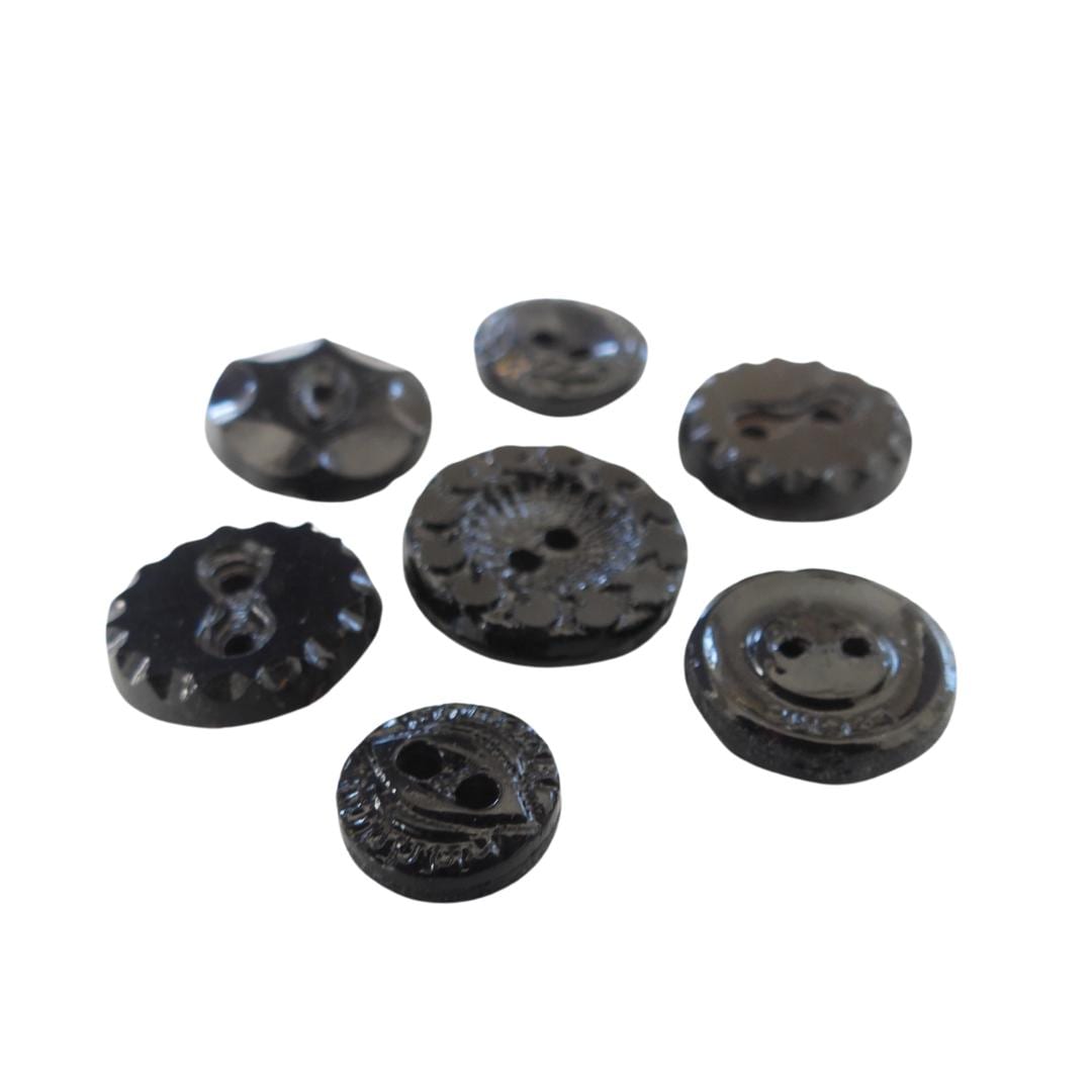 Set of 7 antique Victorian black glass buttons for sewing - 2-hole, 8–15 mm, Czech molded glass. Glossy floral & geometric patterns