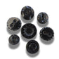 Set of 7 antique Victorian black glass buttons for sewing - 2-hole, 8–15 mm, Czech molded glass. Glossy floral & geometric patterns