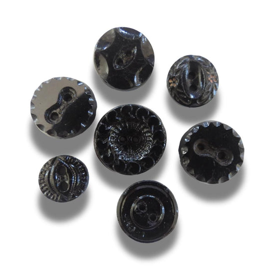 Set of 7 antique Victorian black glass buttons for sewing - 2-hole, 8–15 mm, Czech molded glass. Glossy floral & geometric patterns