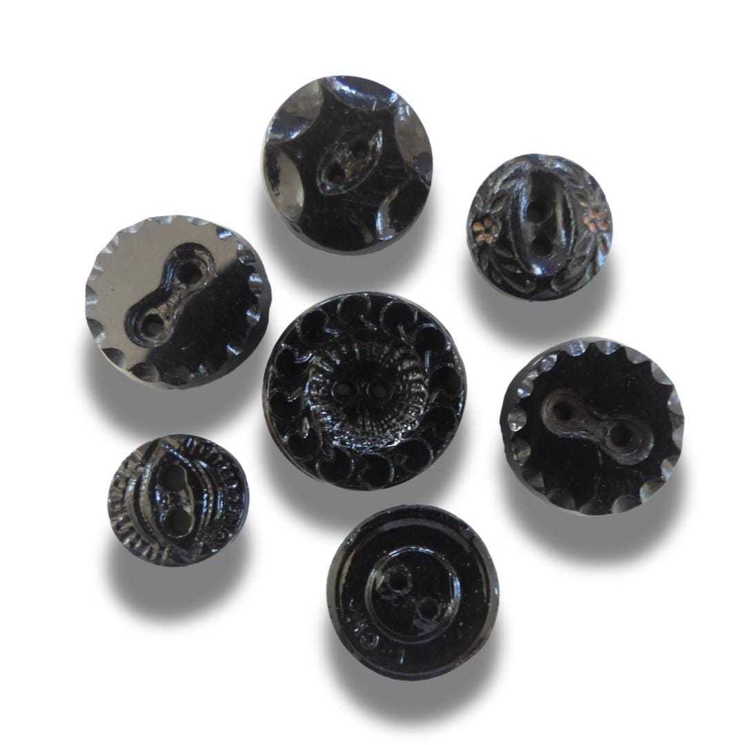 Set of 7 antique Victorian black glass buttons for sewing - 2-hole, 8–15 mm, Czech molded glass. Glossy floral & geometric patterns